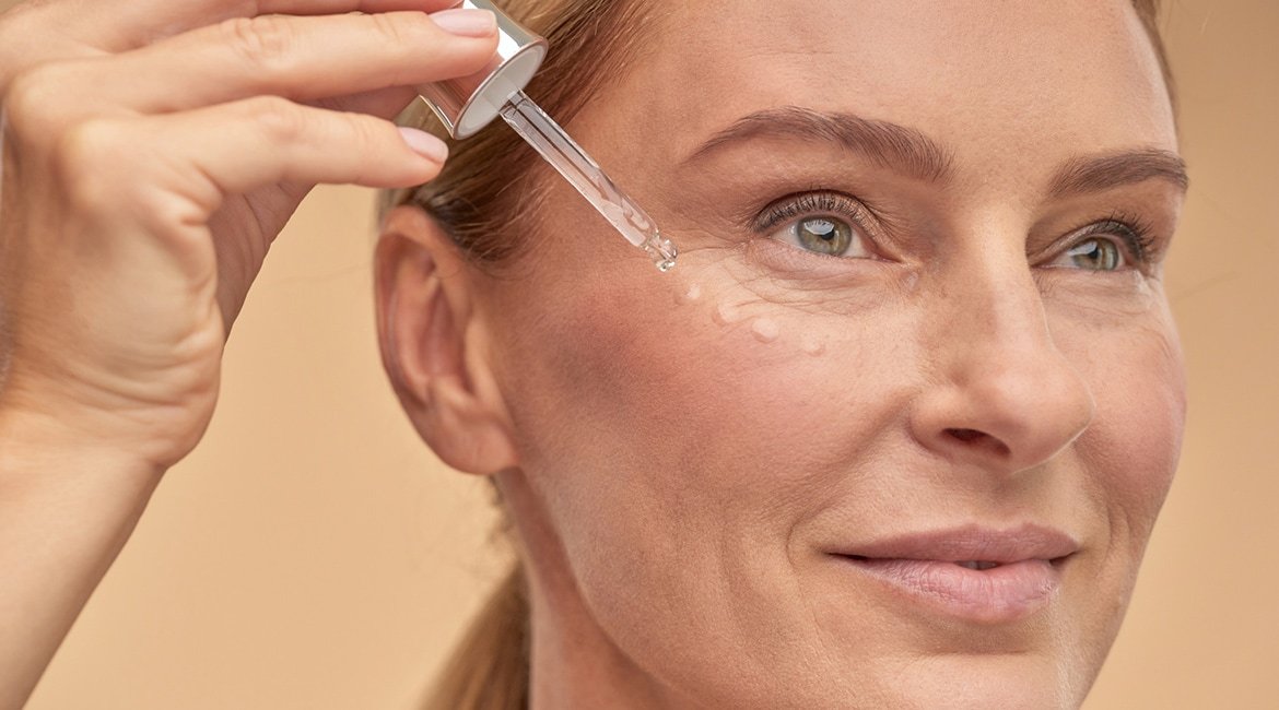 Frau trägt Serum aus einer Pipette auf den Wangenknochen auf